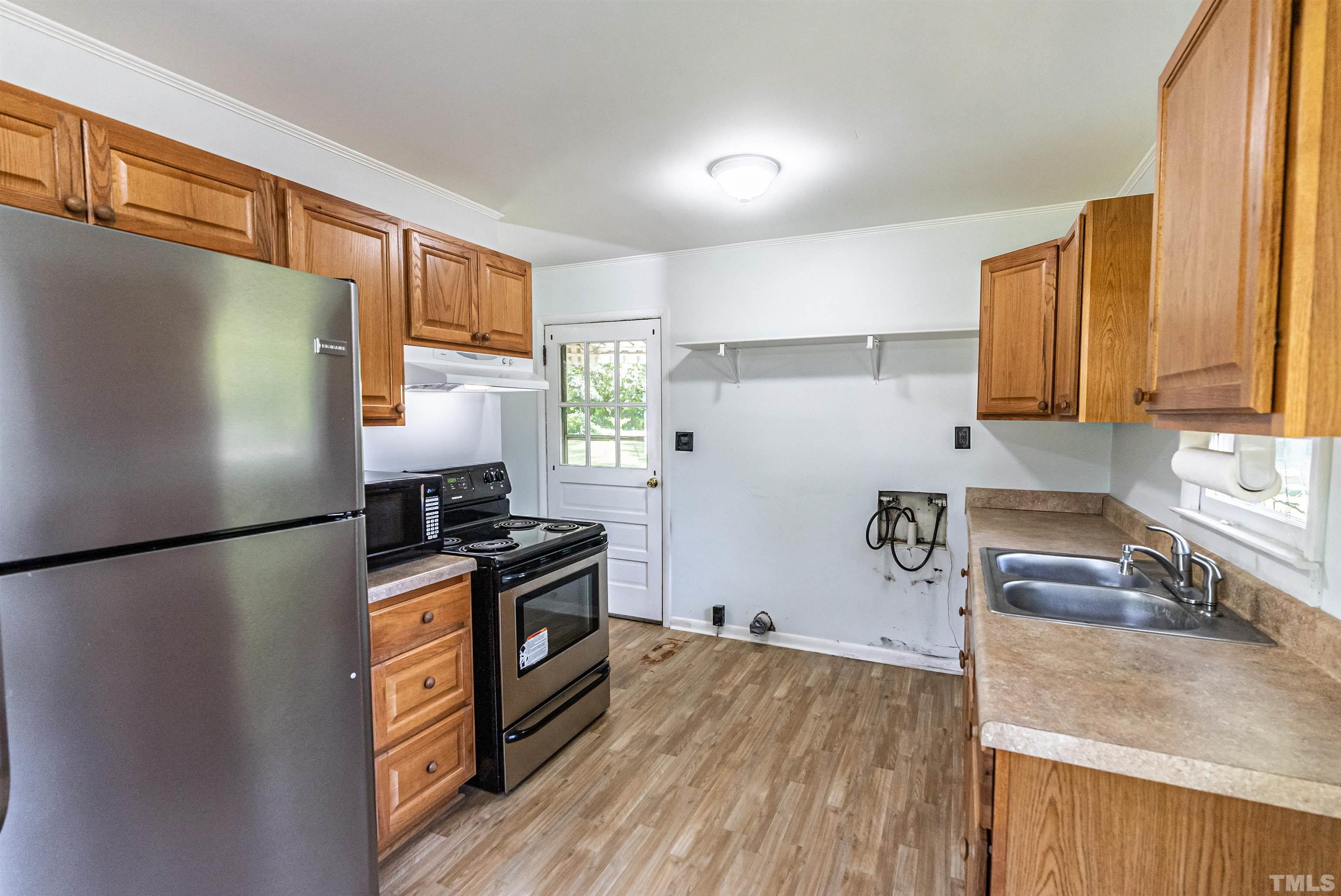 457 Rose Lane Raleigh, NC 27610 - Photo 9 of 26 a kitchen with granite countertop a refrigerator a stove a sink a washer and wooden cabinets