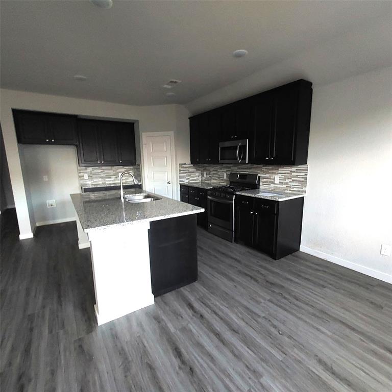 1813 Huntsman Way Forney, TX 75126 - Photo 6 of 18 a kitchen with stainless steel appliances kitchen island granite countertop a stove top oven a sink and dishwasher with wooden floor