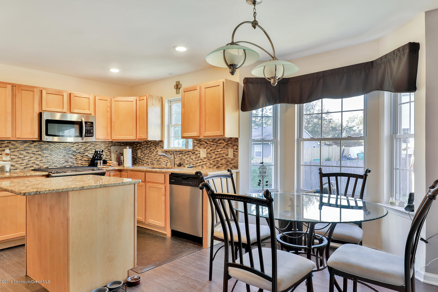 112 Seaspray Road Manahawkin, NJ 08050 - Photo 4 of 21 a kitchen with stainless steel appliances granite countertop a stove top oven a sink dishwasher a dining table and chairs with wooden floor