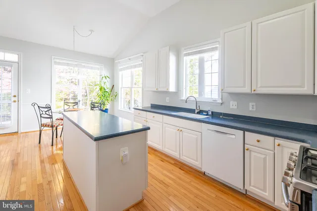 a kitchen with granite countertop a stove a sink and white cabinets with wooden floor