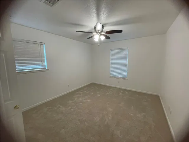 an empty room with a window and ceiling fan