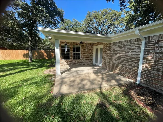 a backyard of a house with plants and large tree