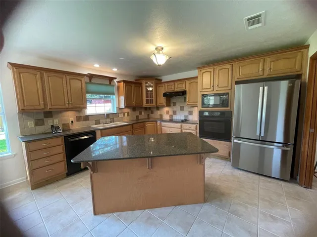 a kitchen with stainless steel appliances granite countertop a stove a refrigerator a sink a microwave and island
