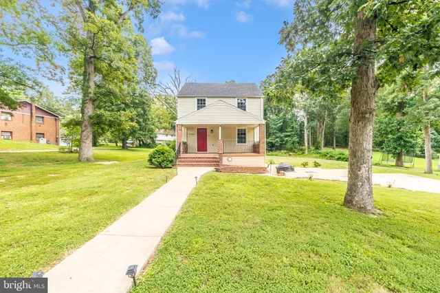 a view of swimming pool with lawn chairs and large trees