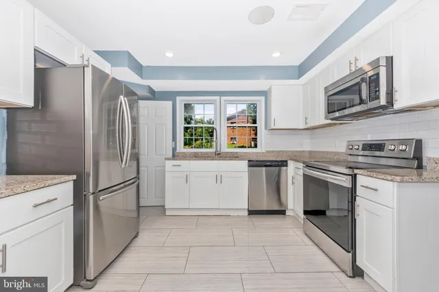 a kitchen with stainless steel appliances granite countertop a refrigerator sink and stove