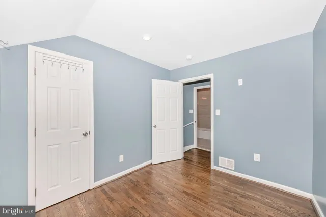 a view of an empty room with wooden floor and closet