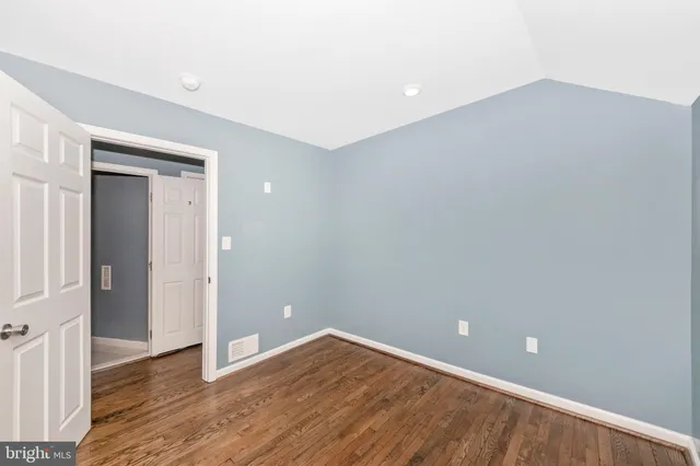 a view of an empty room with wooden floor and closet