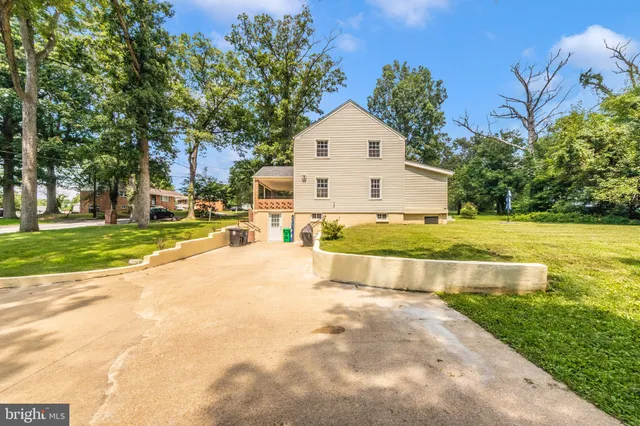 a view of a house with a yard and large trees