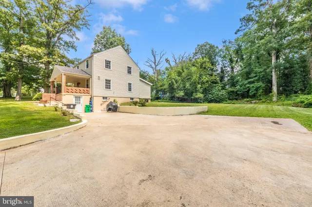a view of a white house with a big yard and large trees