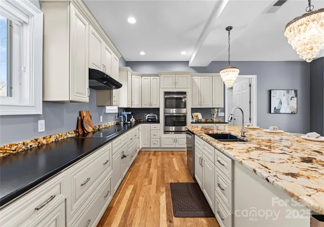 a large kitchen with stainless steel appliances granite countertop a lot of counter space and wooden floors