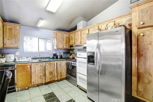 a kitchen with stainless steel appliances granite countertop a refrigerator a sink and white cabinets