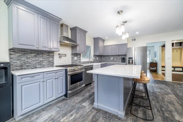 a kitchen with stainless steel appliances granite countertop a sink a stove and a refrigerator