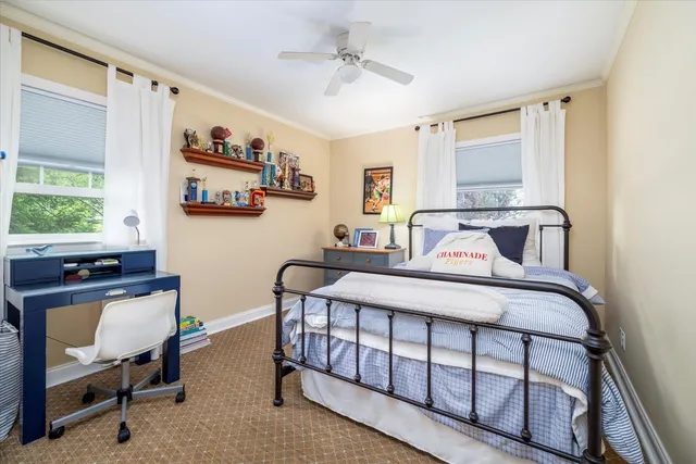 a bedroom with a bed a desk and chair with the wooden floor