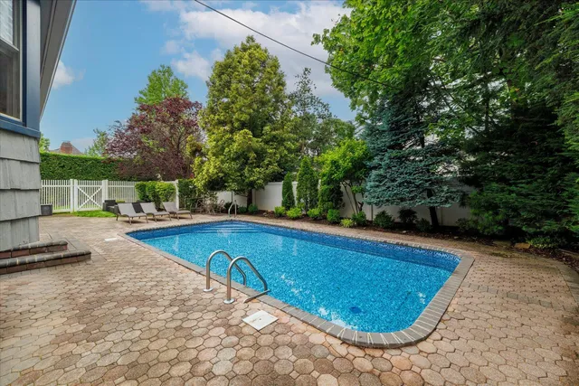 a view of swimming pool with seating space and trees in the background