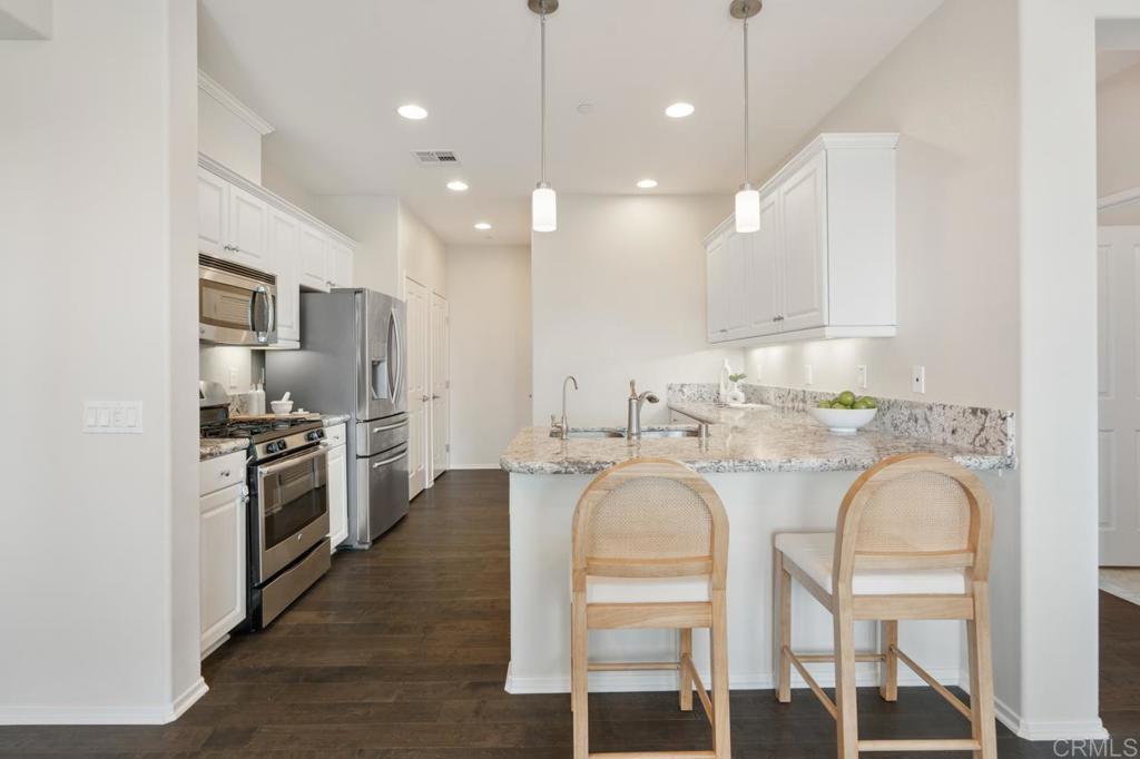 6610 Canopy Ridge Lane, Unit 37 San Diego, CA 92121 - Photo 23 of 65 a kitchen with stainless steel appliances granite countertop a stove top oven a refrigerator a sink and chairs