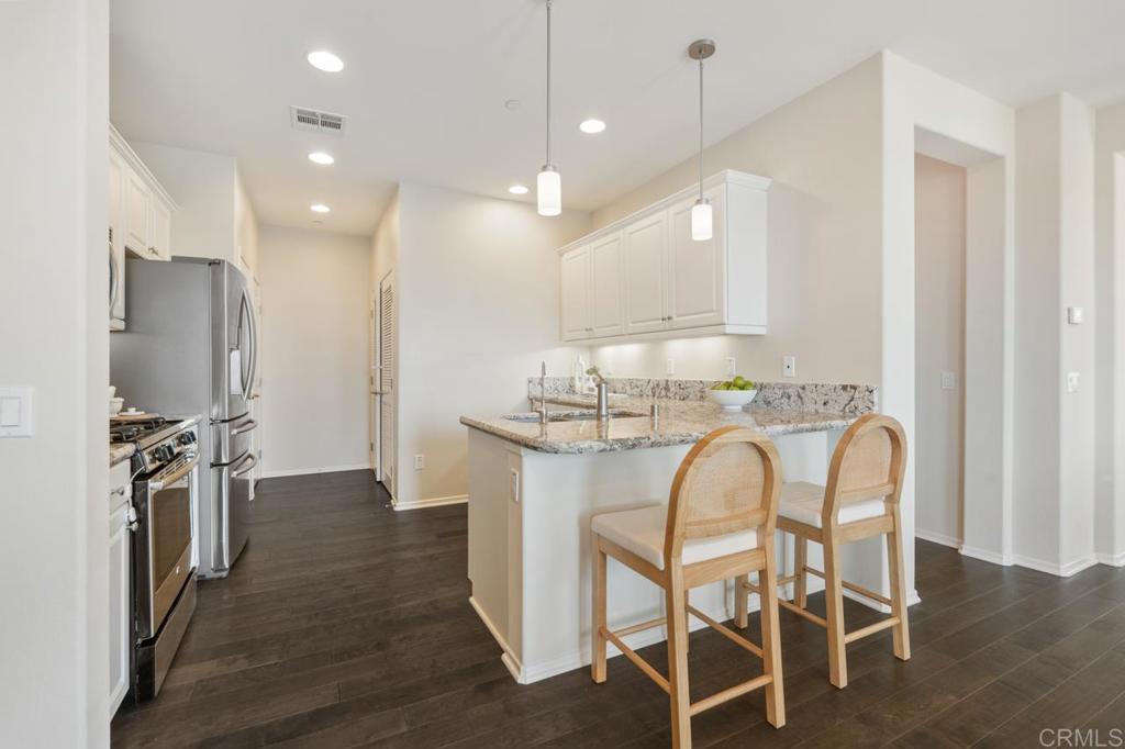 6610 Canopy Ridge Lane, Unit 37 San Diego, CA 92121 - Photo 24 of 65 a kitchen with stainless steel appliances granite countertop a dining table chairs refrigerator and microwave