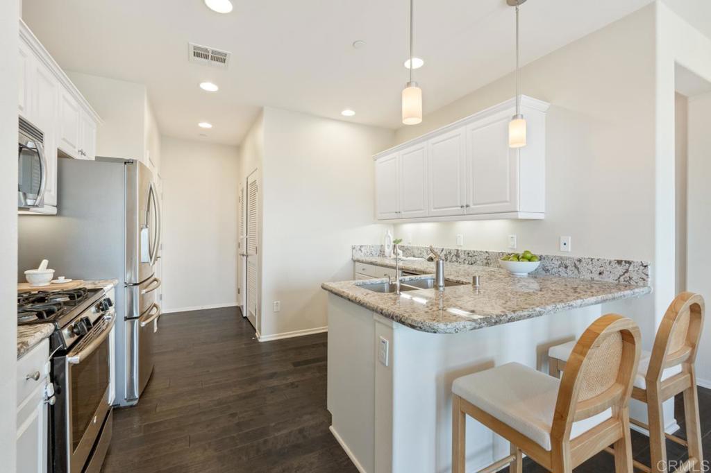 6610 Canopy Ridge Lane, Unit 37 San Diego, CA 92121 - Photo 25 of 65 a kitchen with kitchen island granite countertop a sink and a stove top oven with wooden floor