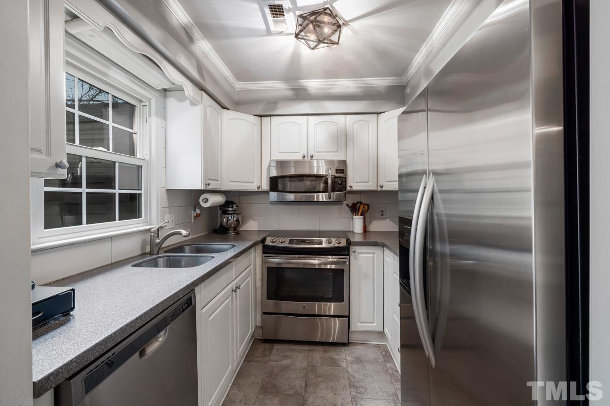 1336 Dylan Heath Court Raleigh, NC 27608 - Photo 13 of 25 a kitchen with kitchen island granite countertop a sink stainless steel appliances and counter space