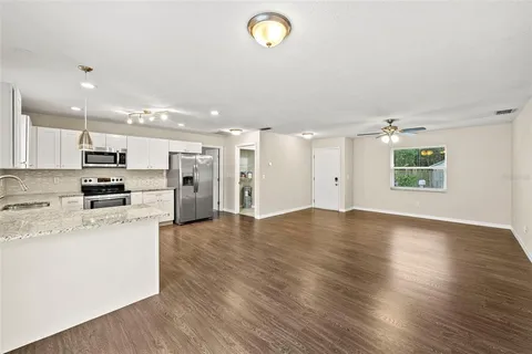 an open kitchen with stainless steel appliances kitchen island a stove and a refrigerator