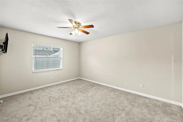an empty room with a window and a ceiling fan