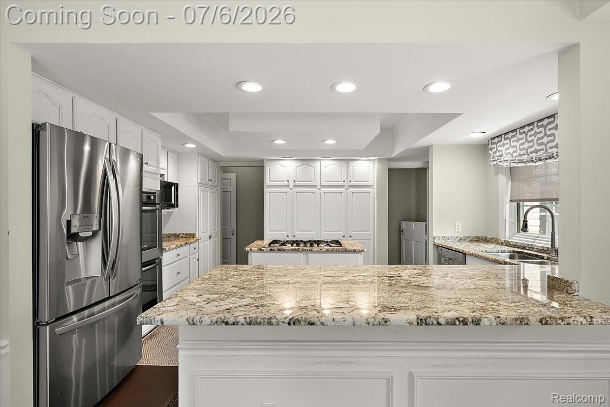 1051 Devonshire Road Grosse Pointe, MI 48230 - Photo 4 of 98 Spacious kitchen featuring extensive stone countertops, white cabinetry, stainless steel appliances, recessed lighting, and a central island with a gas cooktop