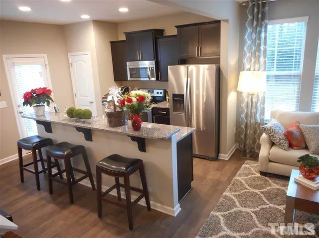 a kitchen with stainless steel appliances kitchen island granite countertop a refrigerator and a dining table
