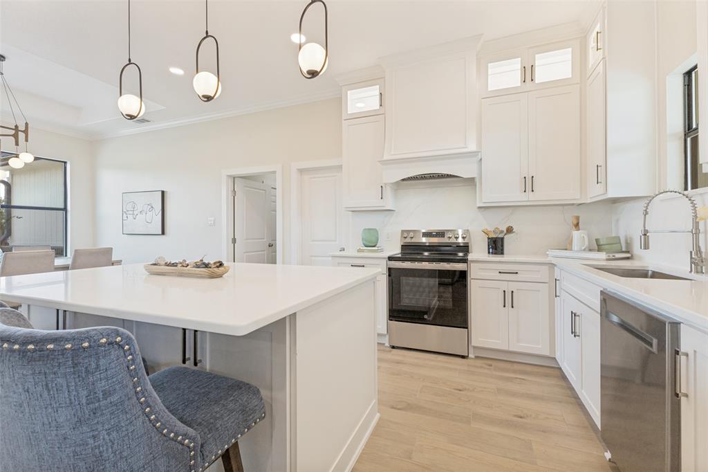 3150 Crisp Road Ennis, TX 75119 - Photo 9 of 30 Contemporary kitchen featuring an island with a light-toned countertop, white cabinetry, stainless steel appliances, and wood-finish flooring