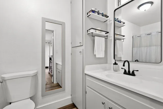 a bathroom with a sink a toilet a mirror and shower