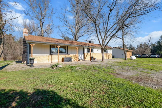 a view of a house with backyard and a tree