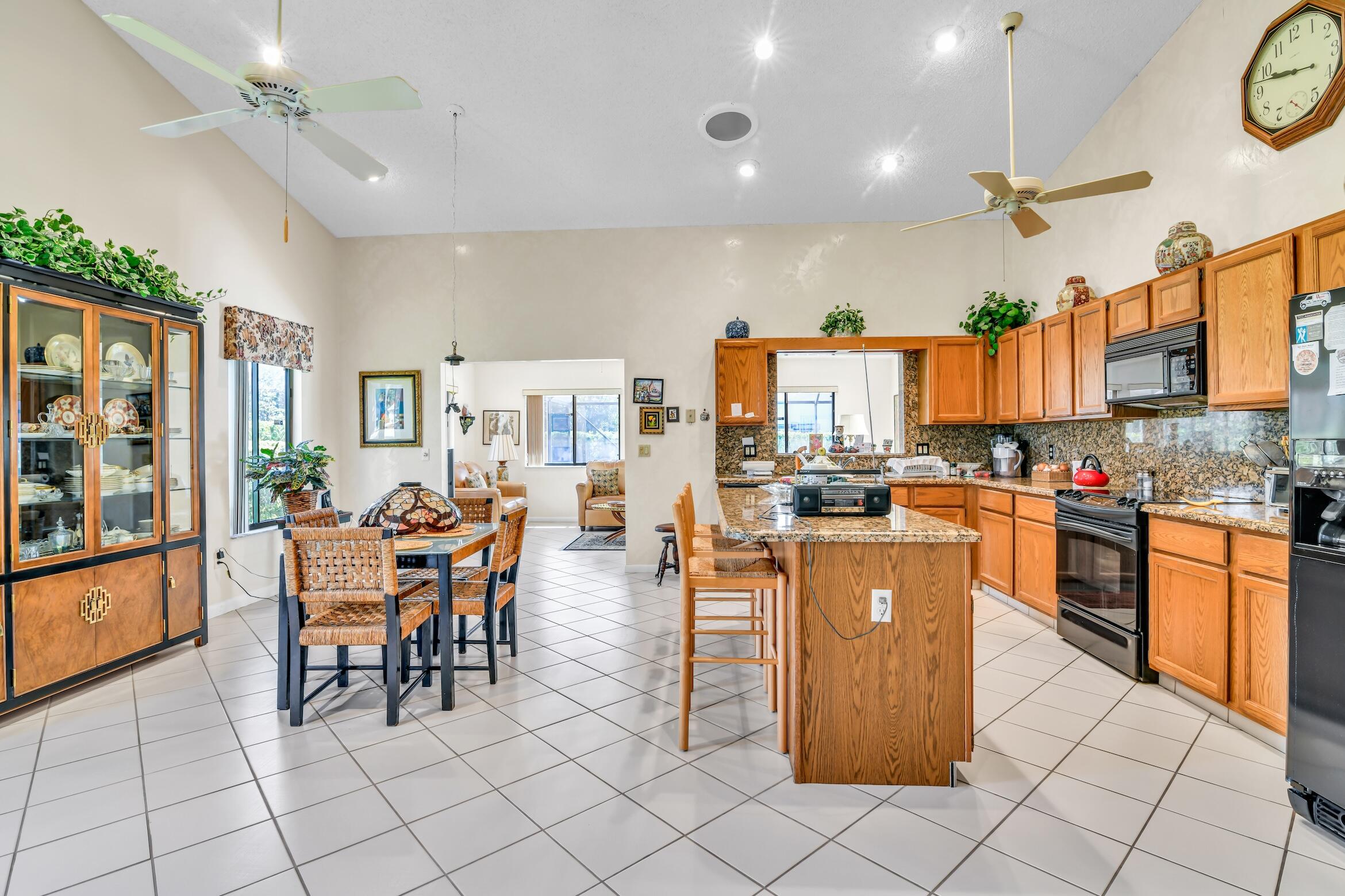 2660 Riviera Drive Delray Beach, FL 33445 - Photo 14 of 40 a kitchen with stainless steel appliances kitchen island granite countertop a table chairs and a stove