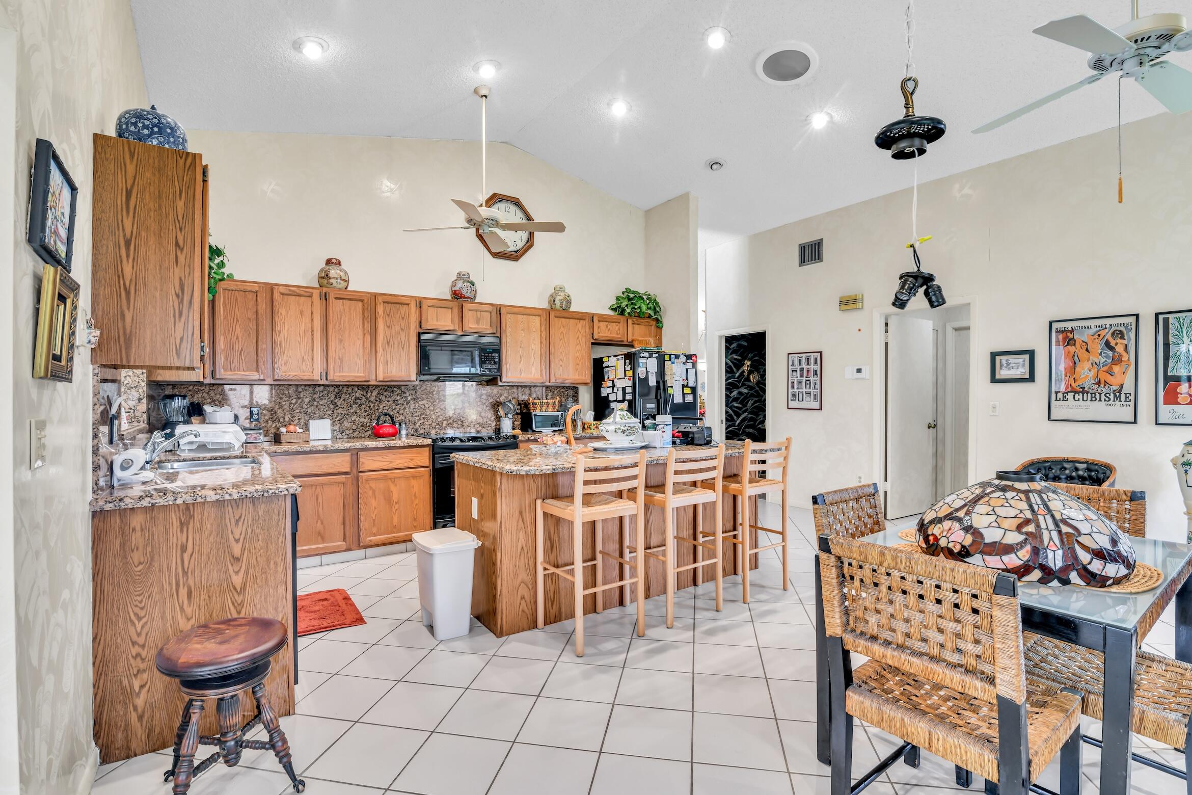 2660 Riviera Drive Delray Beach, FL 33445 - Photo 15 of 40 a kitchen with stainless steel appliances kitchen island granite countertop a table chairs and a refrigerator