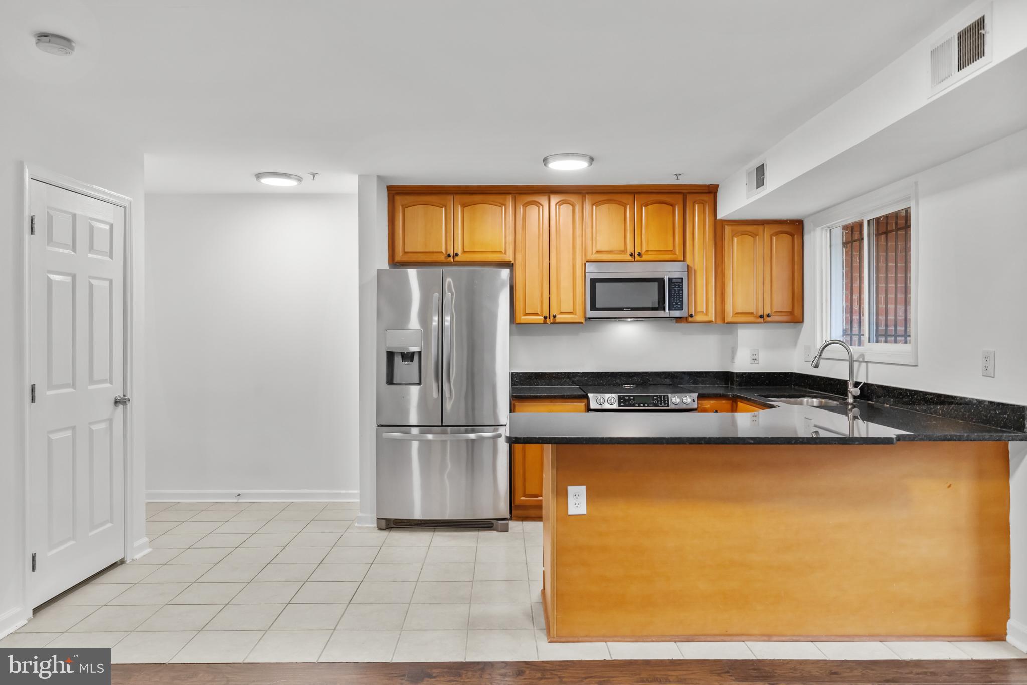 1386 Bryant Street Northeast, Unit 103 Washington, DC 20018 - Photo 6 of 28 a kitchen with granite countertop a refrigerator and a sink