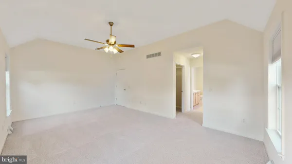 an empty room with windows and fan