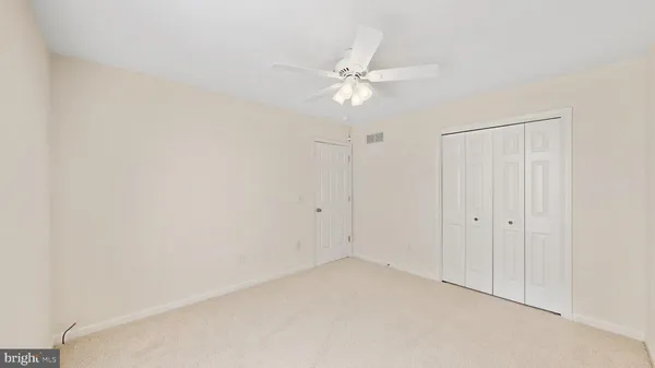 an empty room with closet and ceiling fan