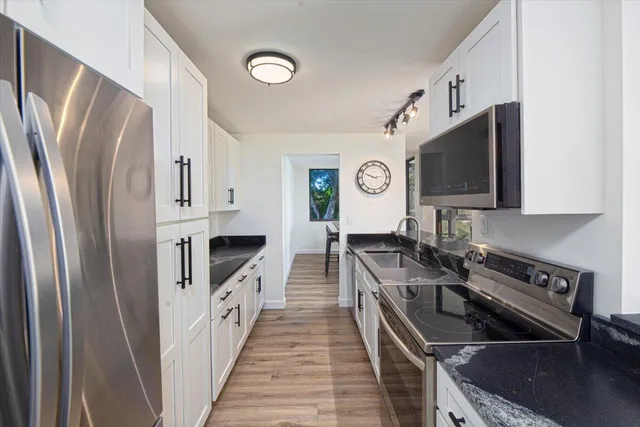 a kitchen with stainless steel appliances granite countertop a refrigerator a stove and a sink
