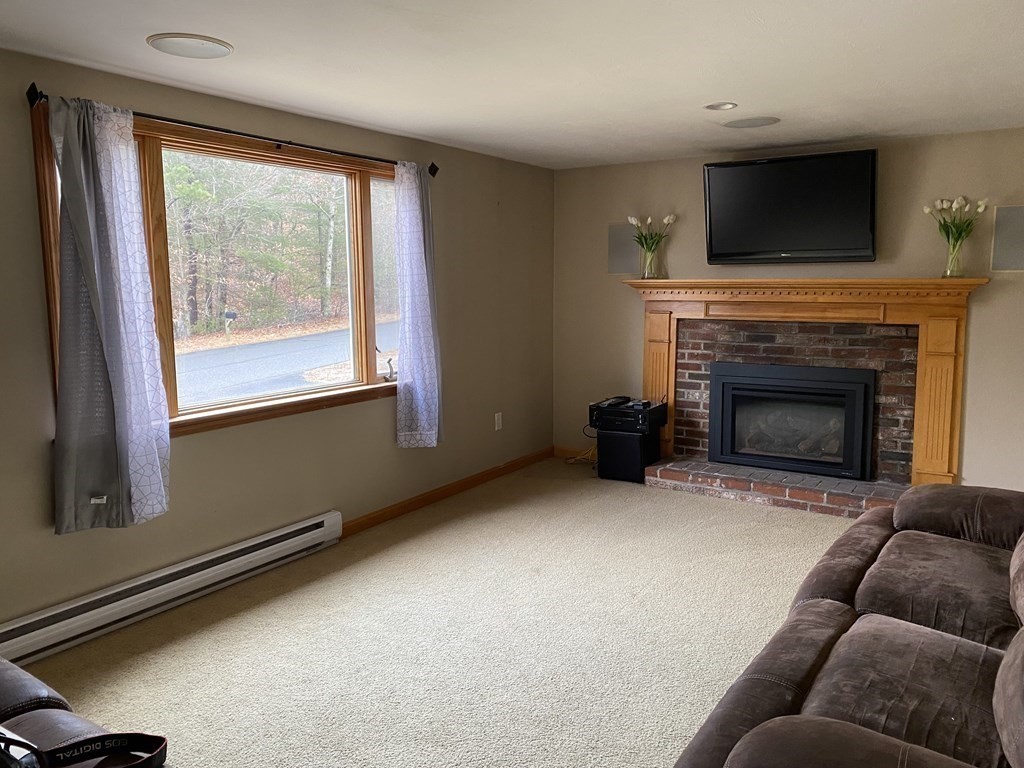 66 Scituate Road Mashpee, MA 02649 - Photo 3 of 33 a living room with furniture a flat screen tv and a fireplace