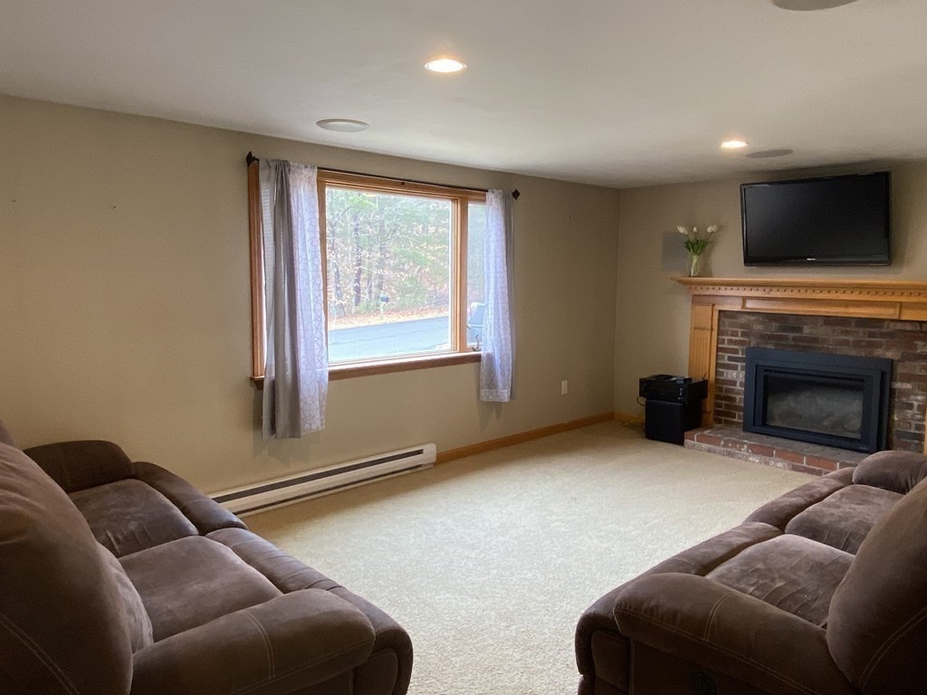 66 Scituate Road Mashpee, MA 02649 - Photo 5 of 33 a living room with furniture a flat screen tv and a fireplace