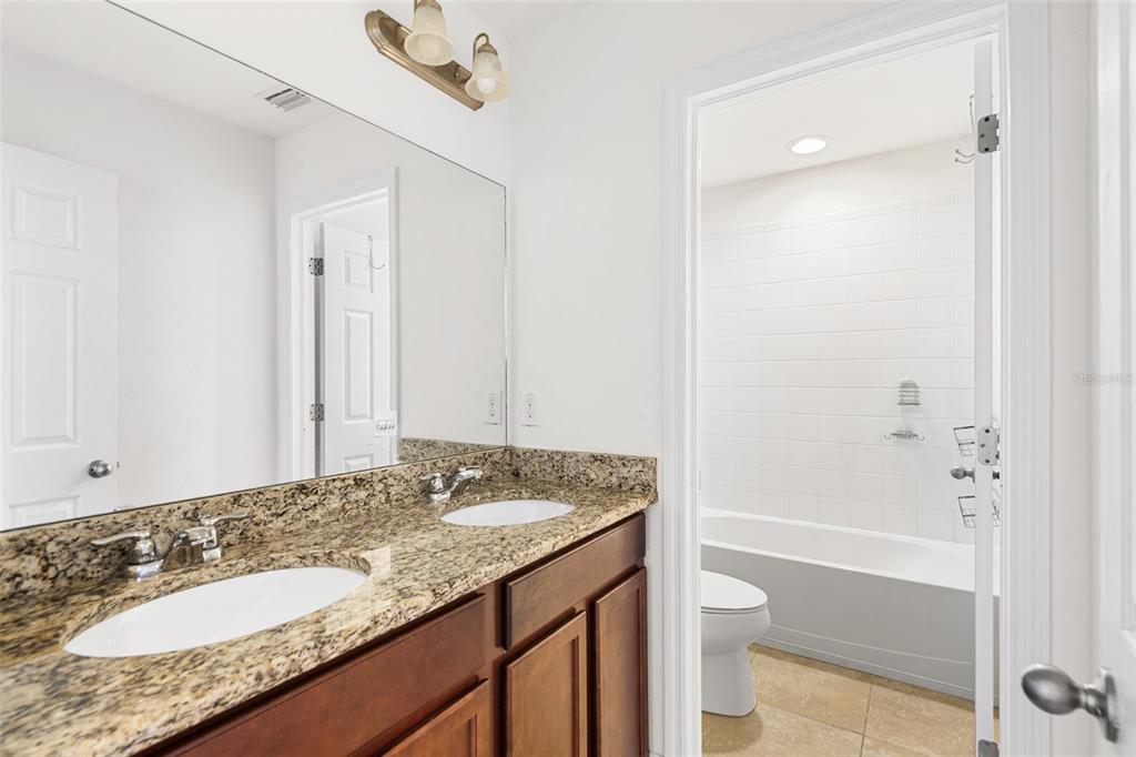 1848 Oak Hammock Court Lutz, FL 33558 - Photo 18 of 25 a bathroom with a granite countertop sink a toilet and shower