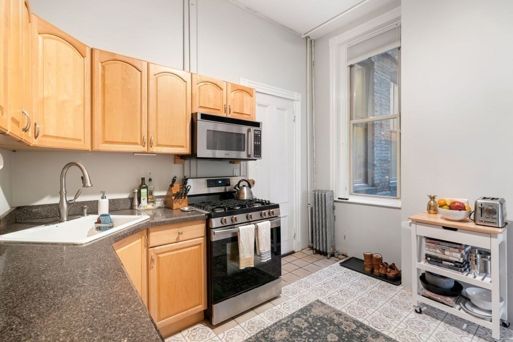 1411 Washington Street, Unit 5 Boston, MA 02118 - Photo 8 of 19 a kitchen with stainless steel appliances granite countertop a stove a sink and a microwave