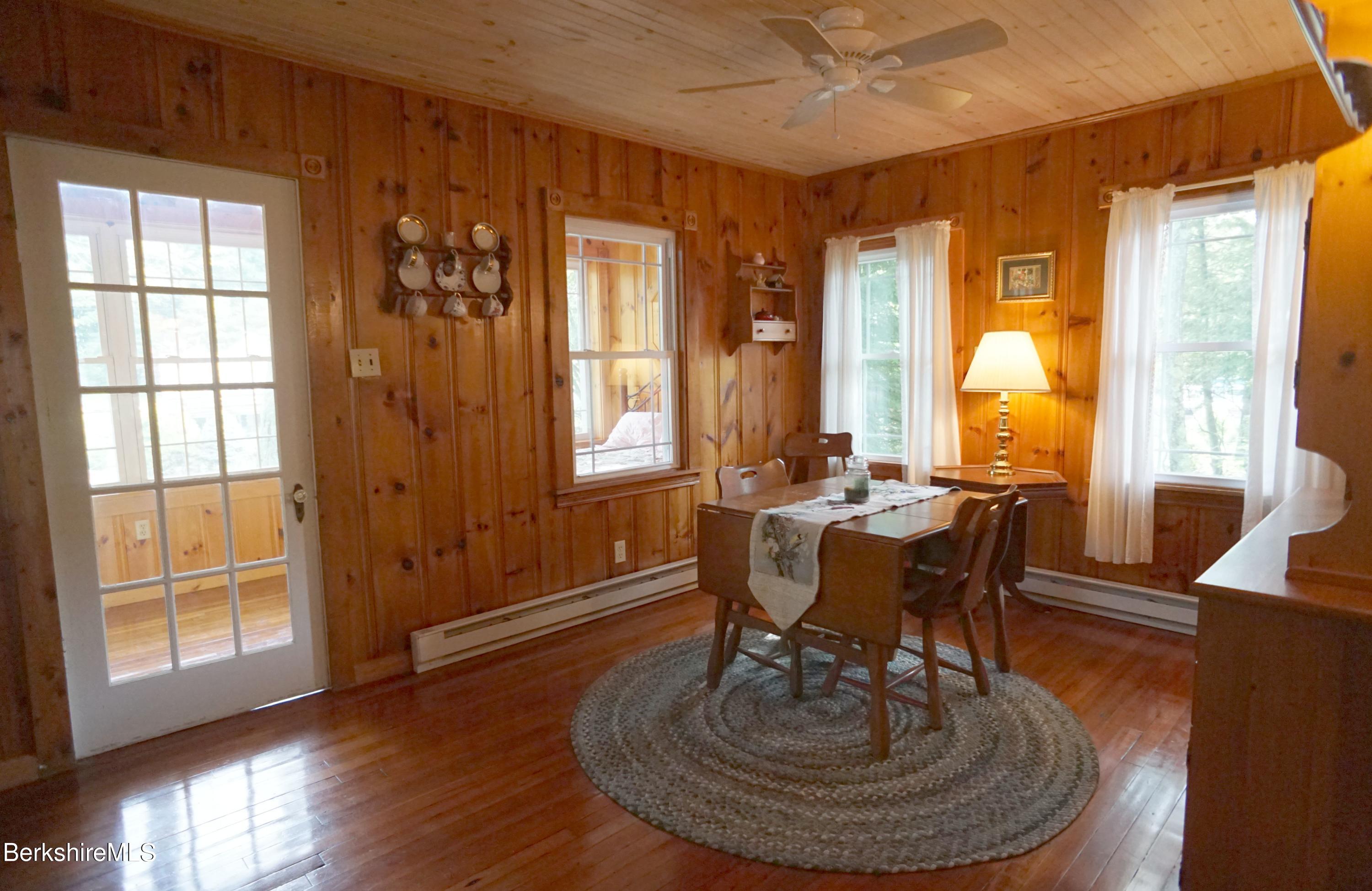 5 South Gate Island Road Otis, MA 01029 - Photo 21 of 38 a dining room with wooden floor a glass table and chairs