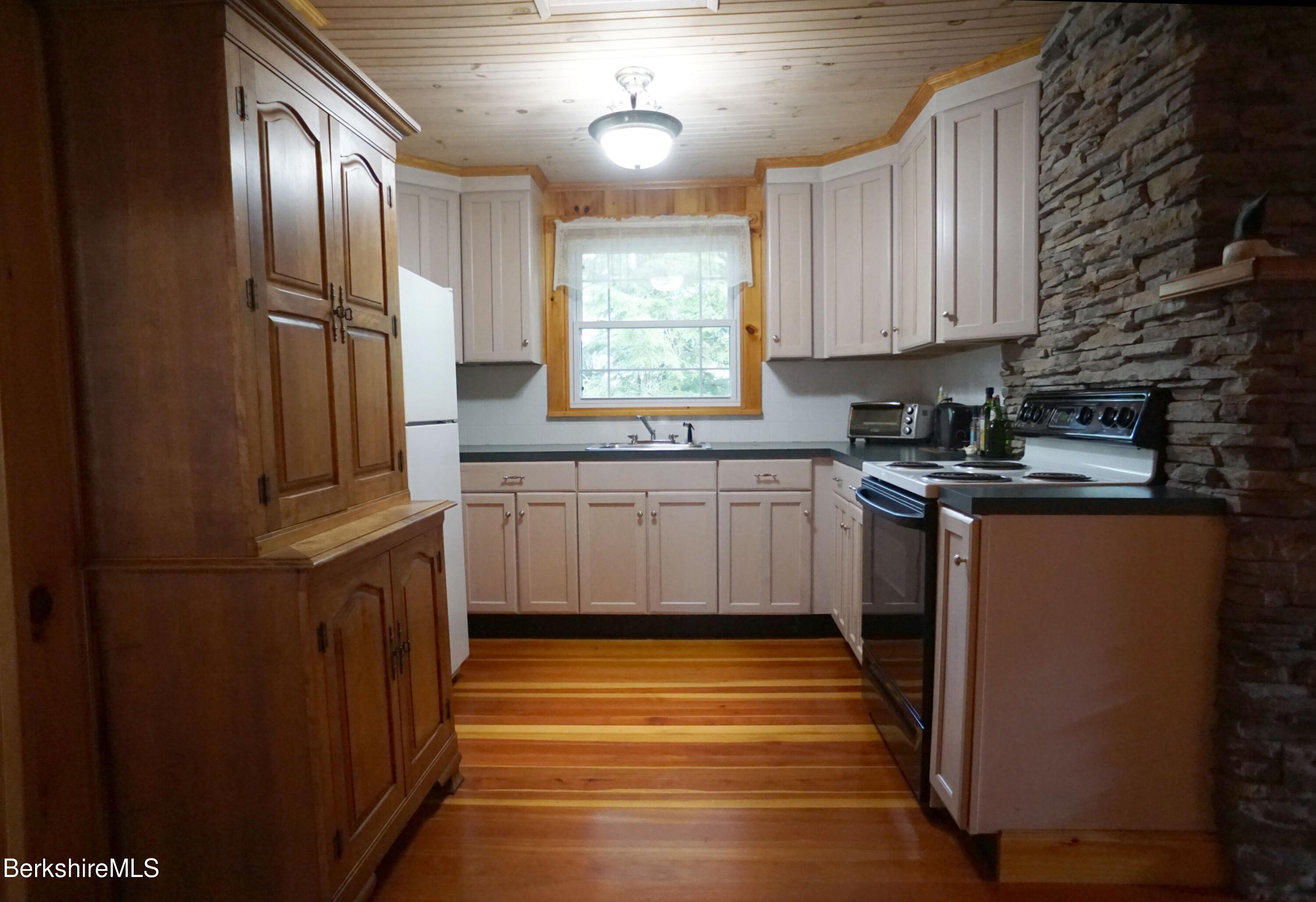 5 South Gate Island Road Otis, MA 01029 - Photo 24 of 38 a kitchen with stainless steel appliances granite countertop a sink a window and wooden cabinets