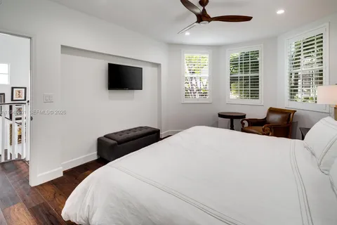 a bedroom with a bed a window and a flat screen tv