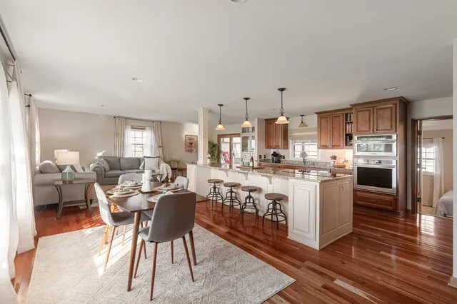 a kitchen with stainless steel appliances kitchen island granite countertop a table chairs and a refrigerator