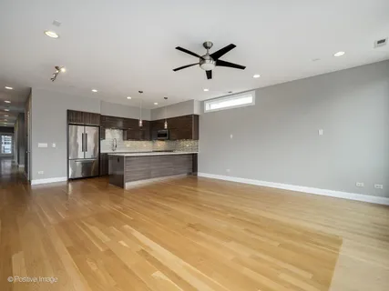a view of kitchen and empty room with wooden floor