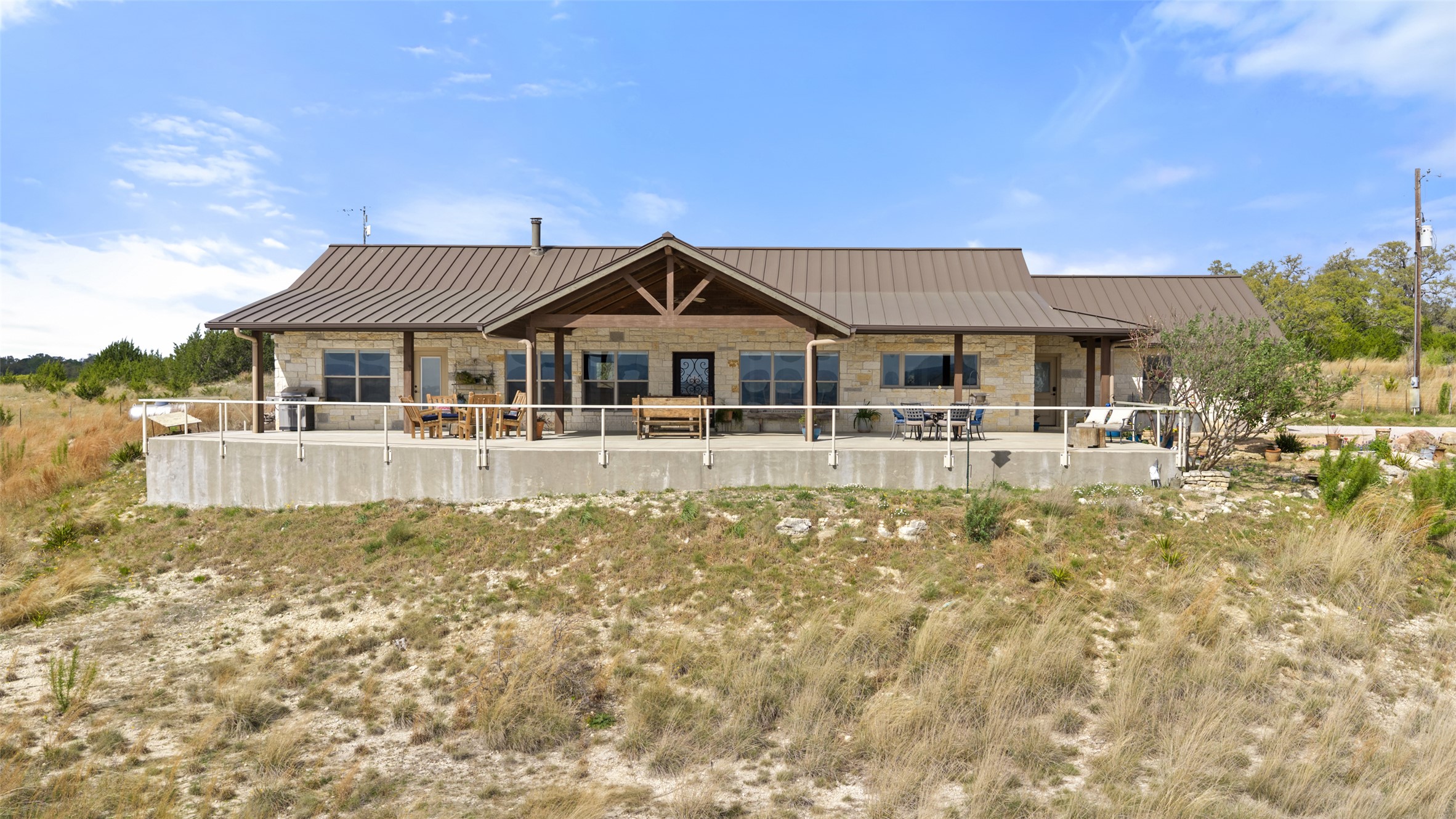 546 Lazy Oak Road Hye, TX 78635 - Photo 25 of 34 Rear view of property featuring stone siding, a patio area, and a standing seam roof