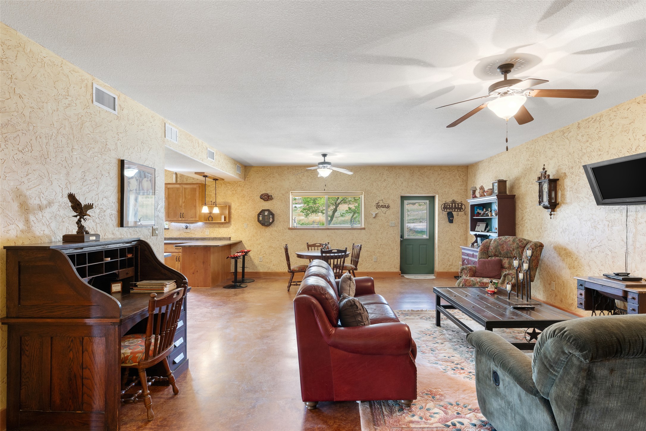 546 Lazy Oak Road Hye, TX 78635 - Photo 30 of 34 Living area featuring concrete flooring, a ceiling fan, wallpapered walls, and a textured ceiling