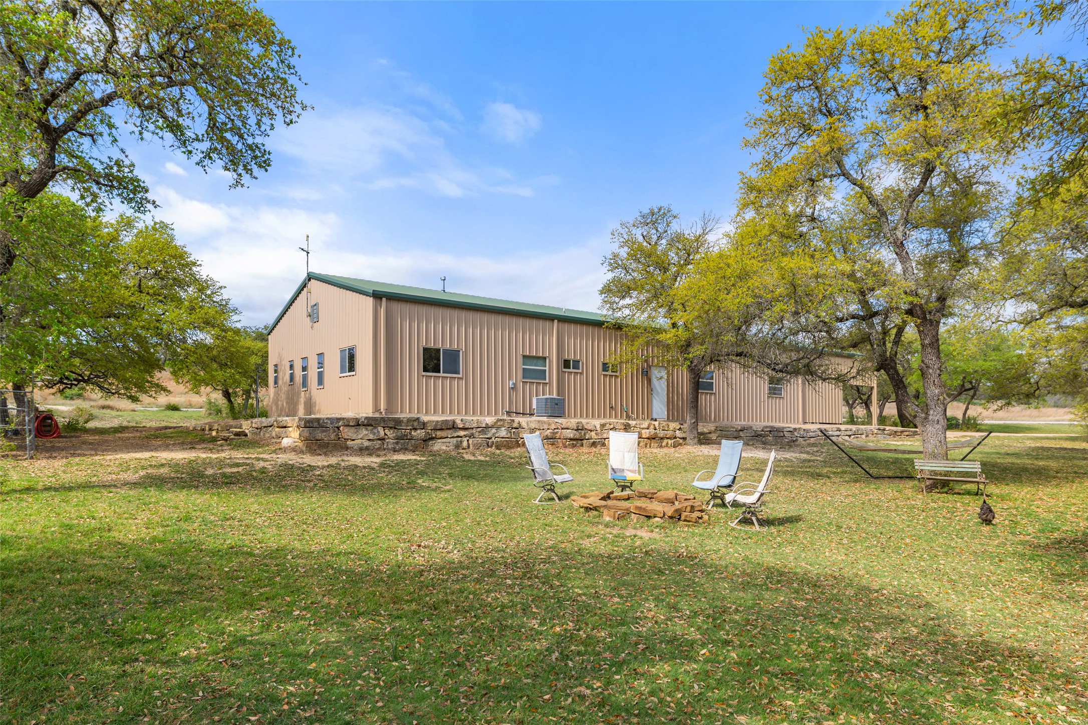 546 Lazy Oak Road Hye, TX 78635 - Photo 33 of 34 Rear view of property with an outdoor fire pit, a lawn, and board and batten siding
