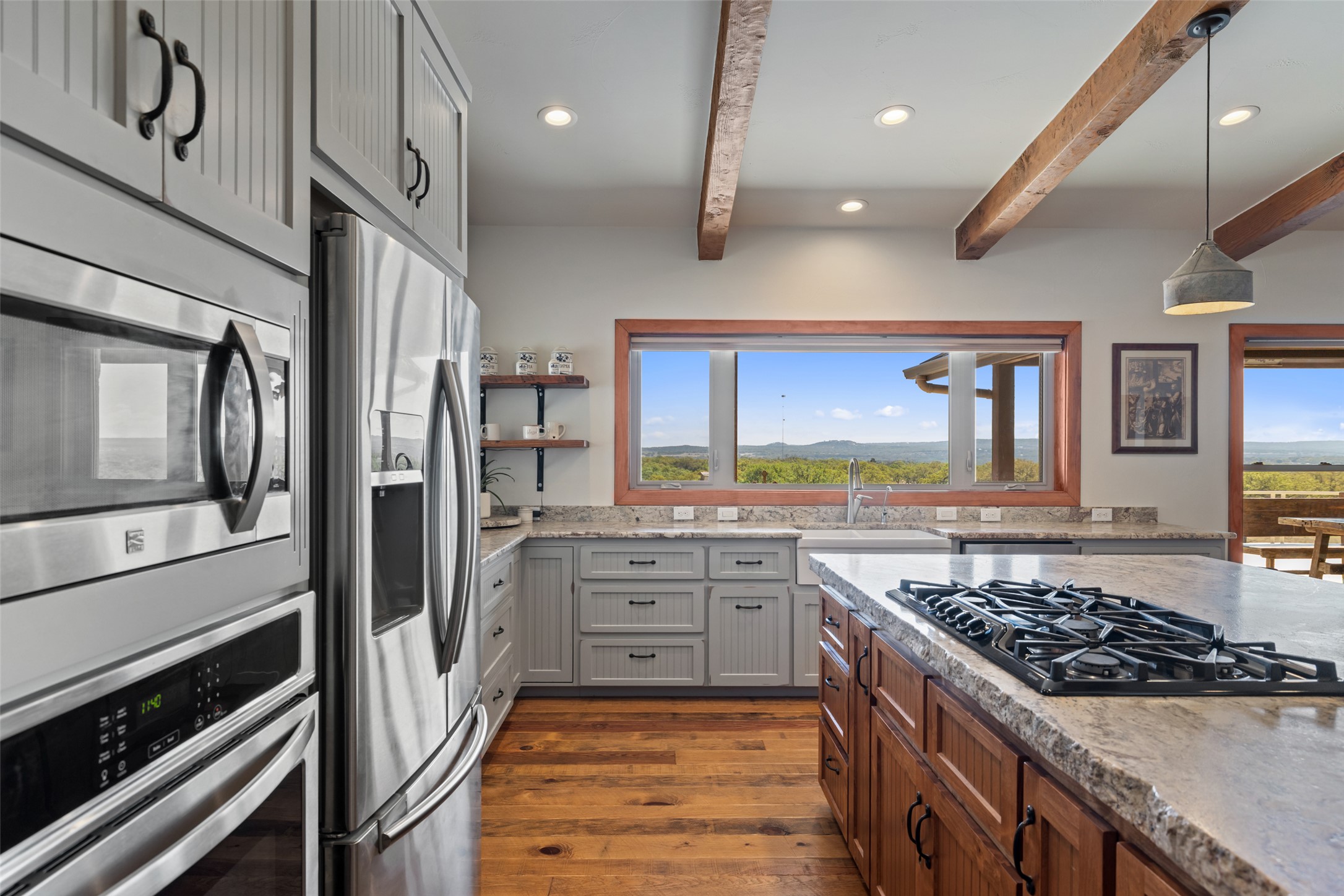 546 Lazy Oak Road Hye, TX 78635 - Photo 6 of 34 Kitchen featuring stainless steel appliances, two tone color scheme, light stone counters, open shelves, and plenty of natural light