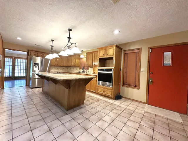 a large kitchen with stainless steel appliances granite countertop a refrigerator and a stove top oven