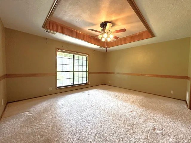 en empty room with windows and ceiling fan